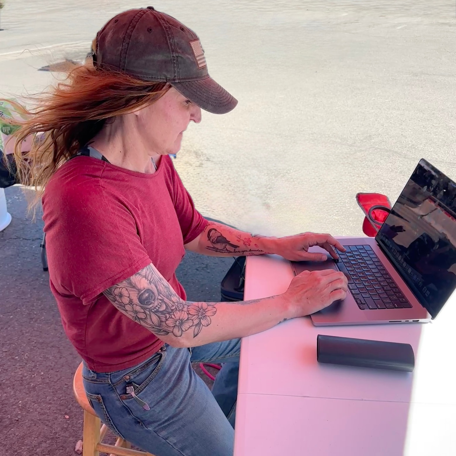 Marylou working on her laptop outdoors at a market table